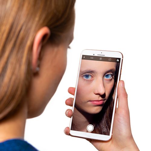 girl looking at herself with a smart phone