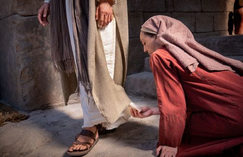 una mujer toca el manto de Jesús