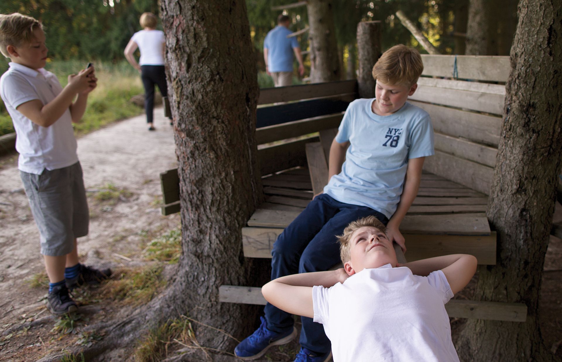 The Karlssons stop at a playground. Mats (right) peers up into the fir trees while talking to his brothers, Magnus (left) and Mikkel (center right).