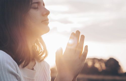 Eine junge Frau schließt die Augen und betet