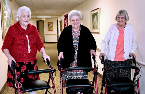 three elderly women with walkers