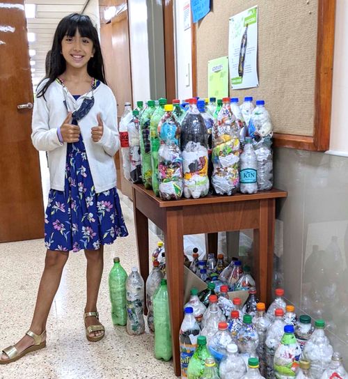 Flicka stående med plastflaskor