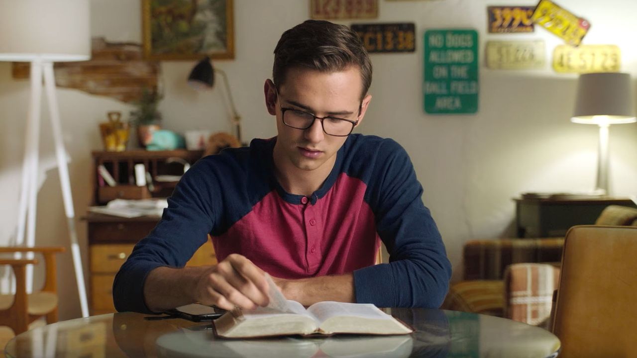 Un hombre joven estudia las Escrituras en la sala de su casa