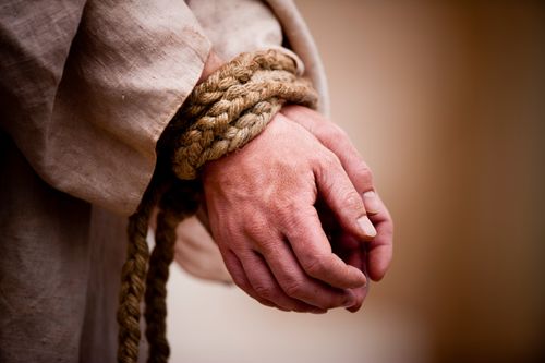 A depiction Christ’s hands tied together tightly with a thick braided rope.