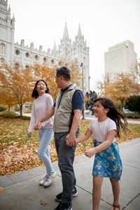 A family is together. They are walking around Temple Square talkig and laughing. You can see the Salt Lake Temple behind them.