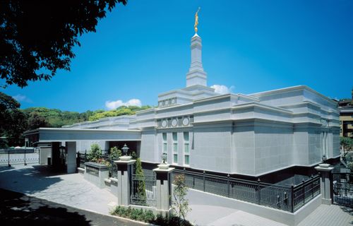 An exterior view of the Fukuoka Japan Temple in the daytime, with a large tree shading the entrance.