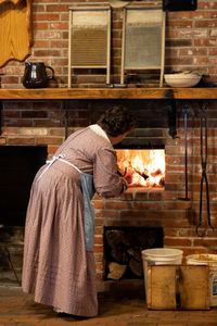 A senior missionary bakes bread in a beehive vven at the Family Living Center in Historic Nauvoo.