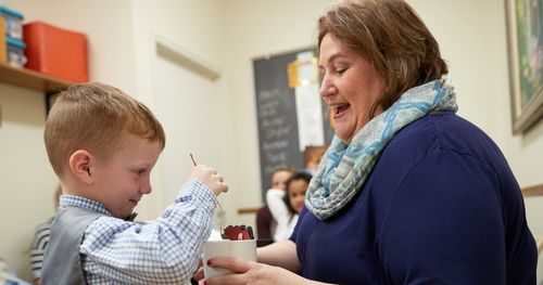 A teacher smiles as she helps a young Primary-age boy during sharing time in Kentucky.