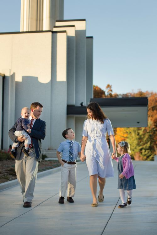 Two parents walk with their three young children on temple grounds.