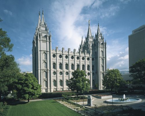A side view of the Salt Lake Temple and grounds, including a fountain and trees.