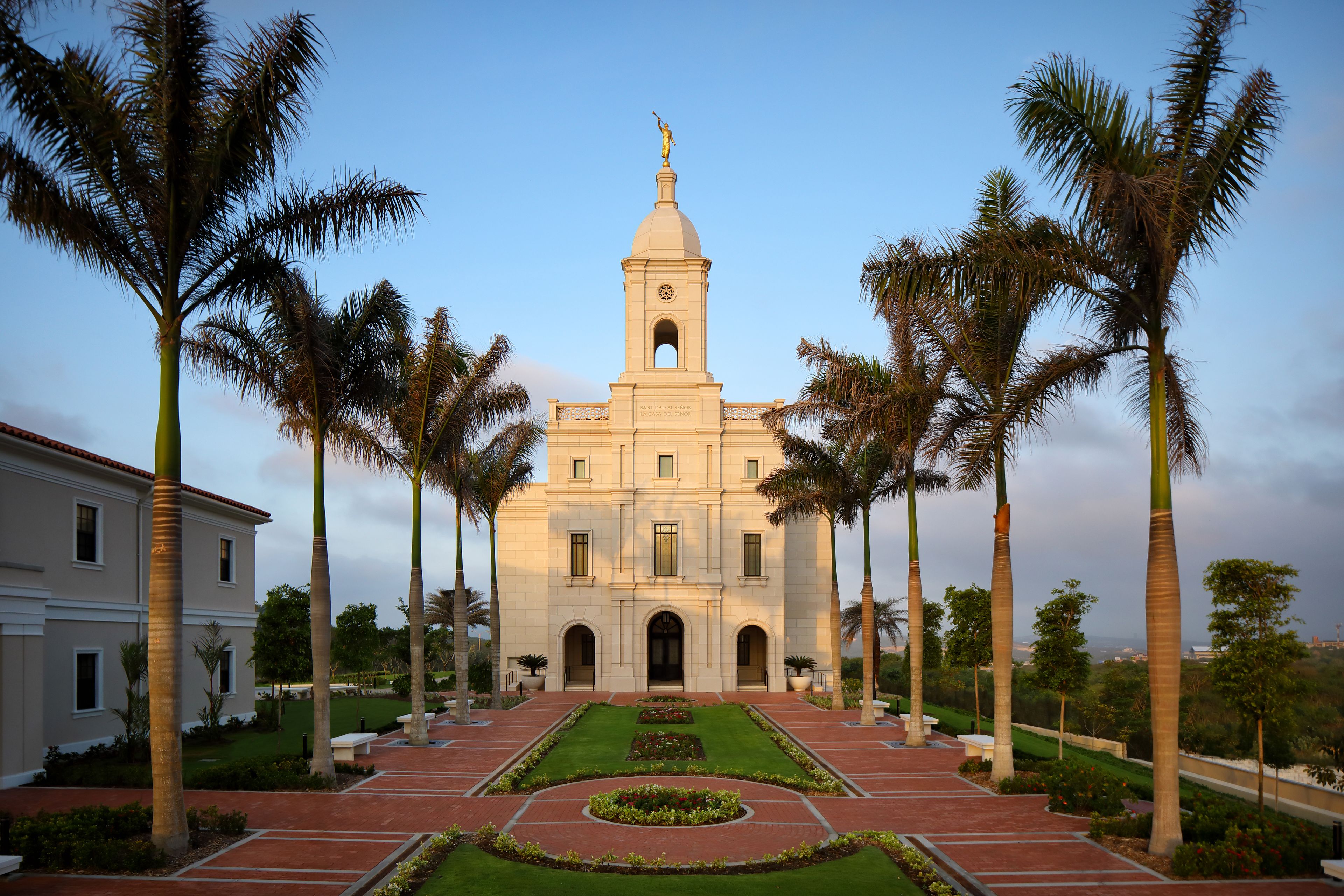A front view of the Barranquilla Colombia Temple, with palm trees lining the walkway to the entrance.
