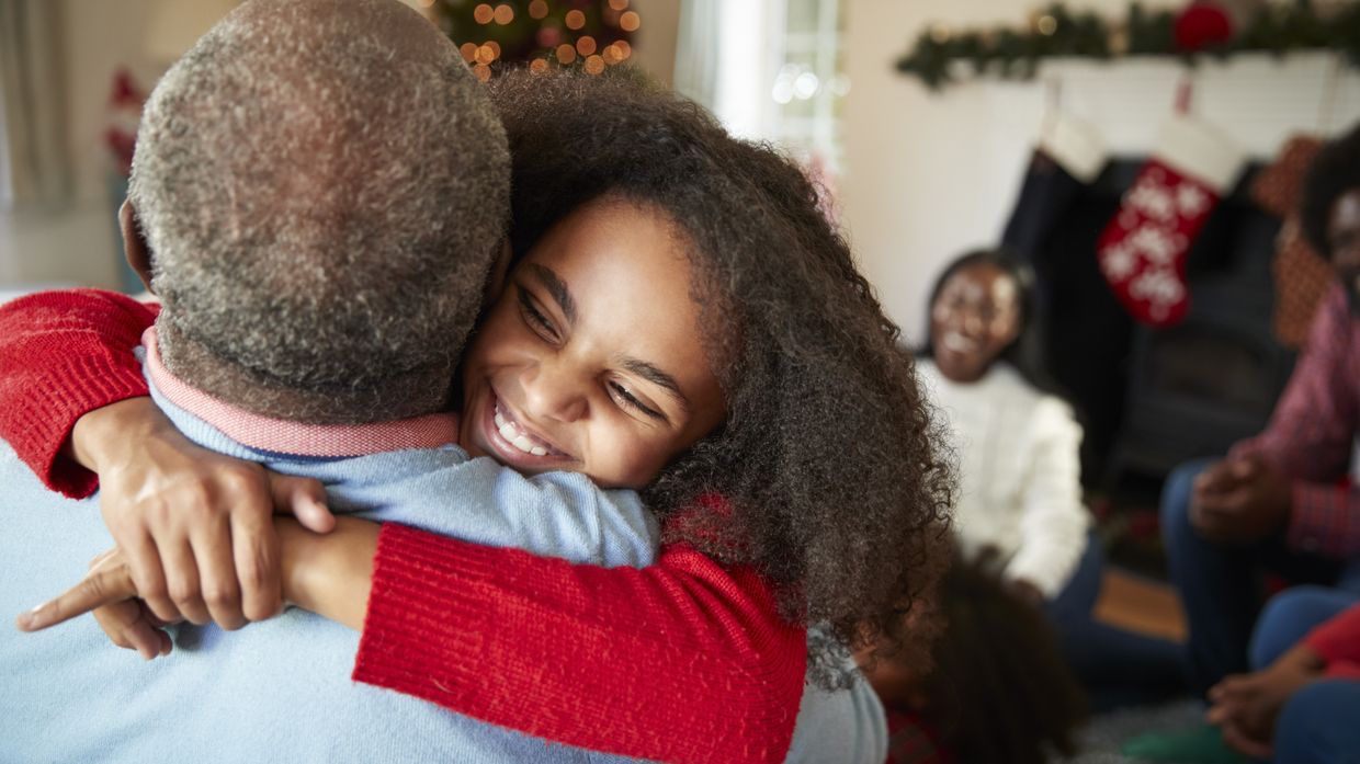 Girl gives her grandfather a hug after receiving a Christmas gift from him