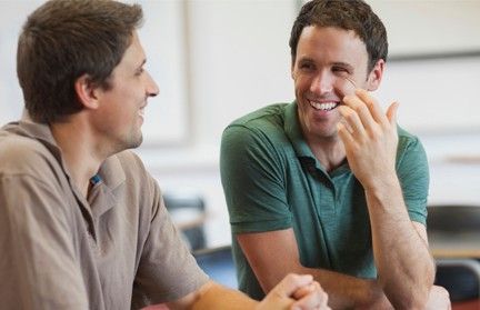 Two men are having a conversation. They appear happy.