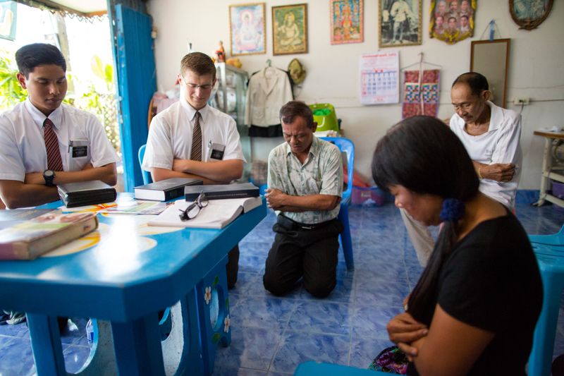Misioneros arrodillados con una familia mientras oran