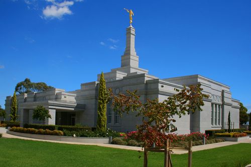 An angled view of the Adelaide Australia Temple in the daytime, with a bright blue sky overhead.