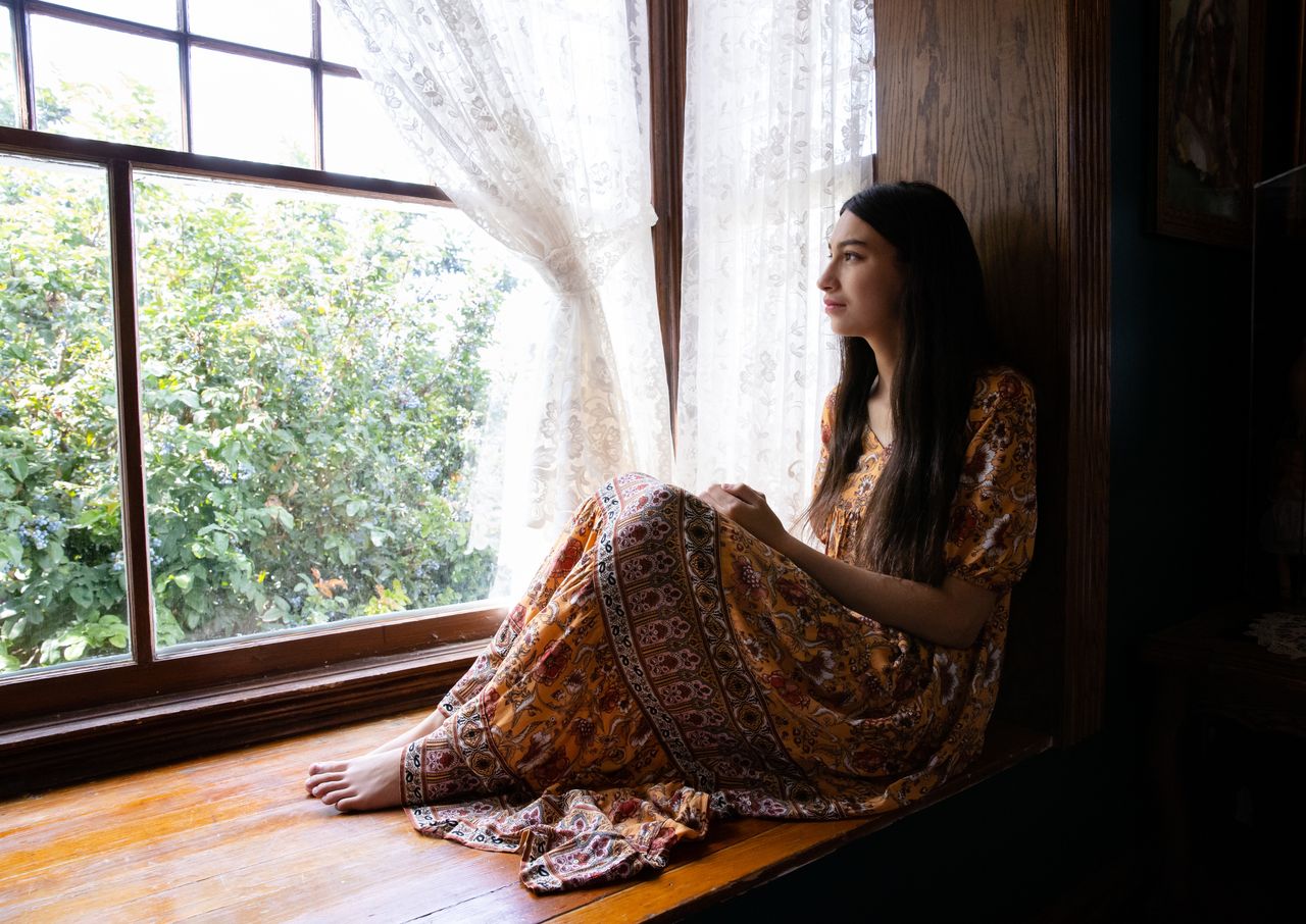 Una joven mira por la ventana pensando en el plan de Dios para ella