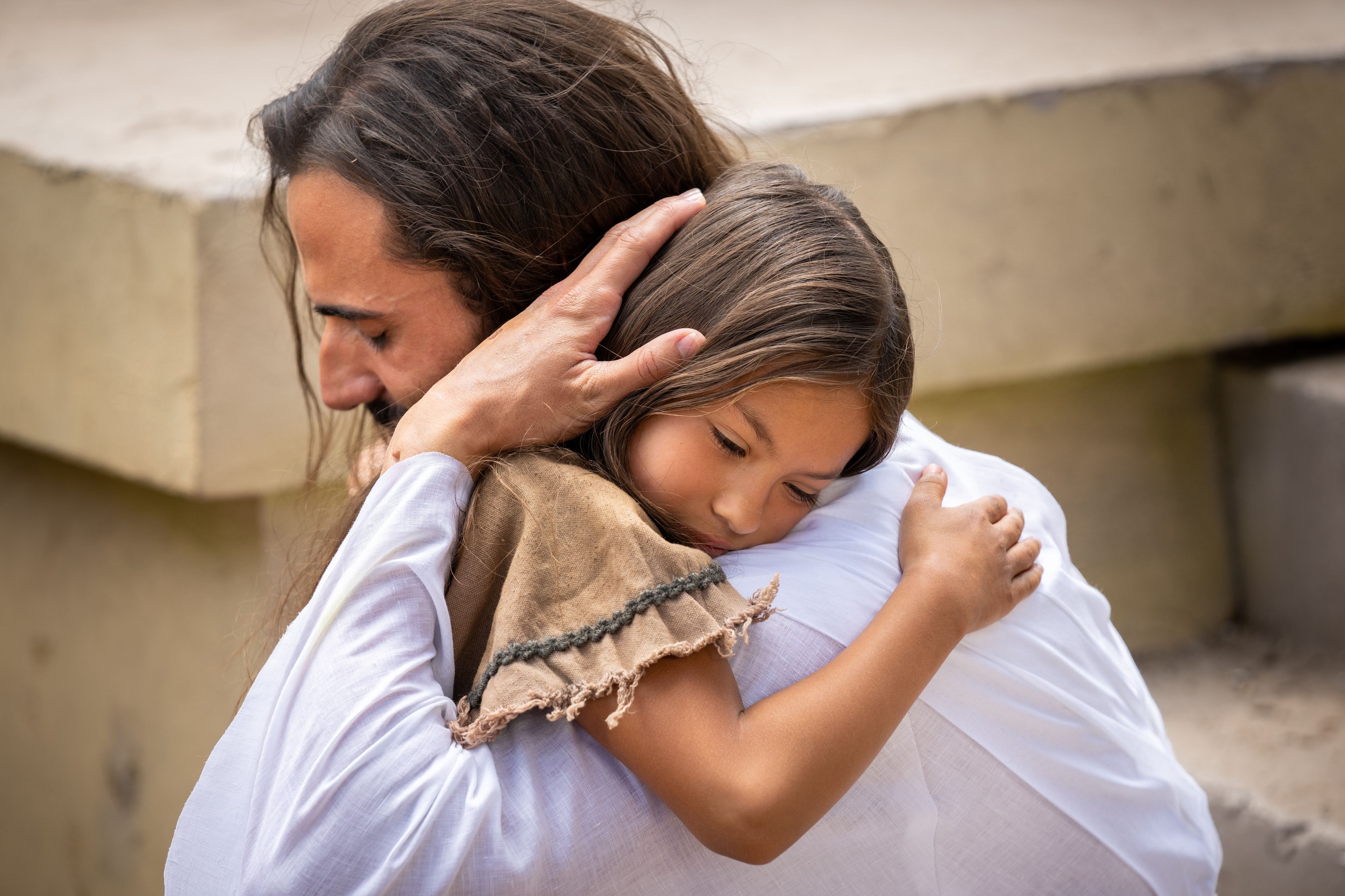 An actor portraying Jesus Christ embraces a young Nephite girl outside.