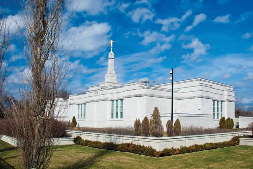 The Montreal Quebec Temple and grounds on a sunny day, with some clouds in the bright blue sky overhead.