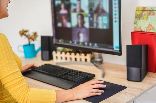 A young woman sits at her computer and has a video conference/zoom/teams meeting.