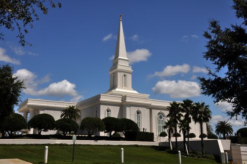 A view of the front of the Orlando Florida Temple, with small trees growing on the grounds and a few white clouds overhead.