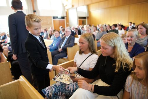 A deacon is passing the sacrament to young women in a congregation in Norway.
