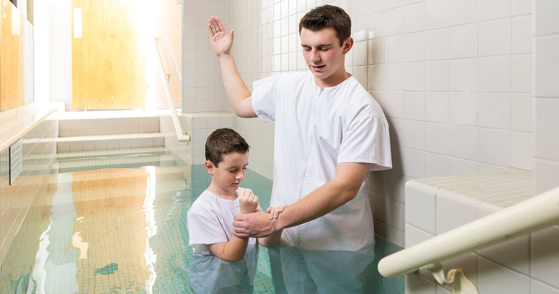 A young man performing the baptism of a boy.