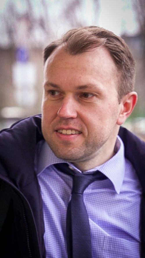 A young man holds the door open for others