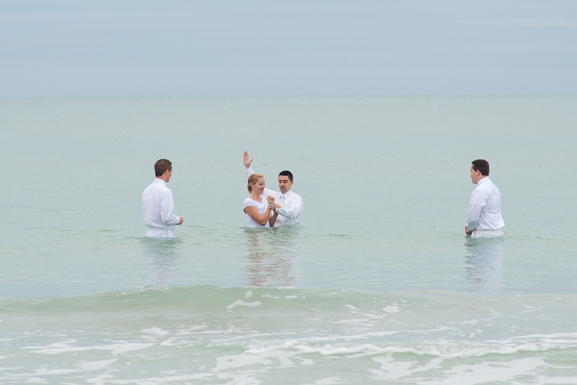 A young woman being baptized in the ocean.