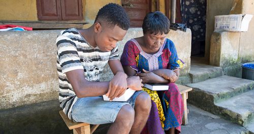Mother and son pray with scriptures in hand in Sierra Leone, Africa.