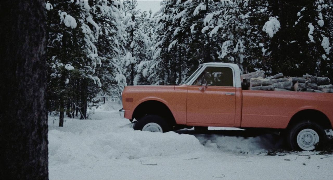 Una camioneta llena de madera conduciendo a través de un banco de nieve