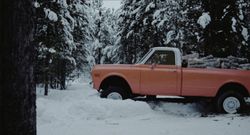 Una camioneta llena de madera conduciendo a través de un banco de nieve