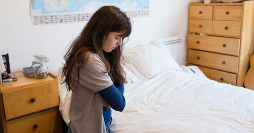 Una joven orando junto a su cama.