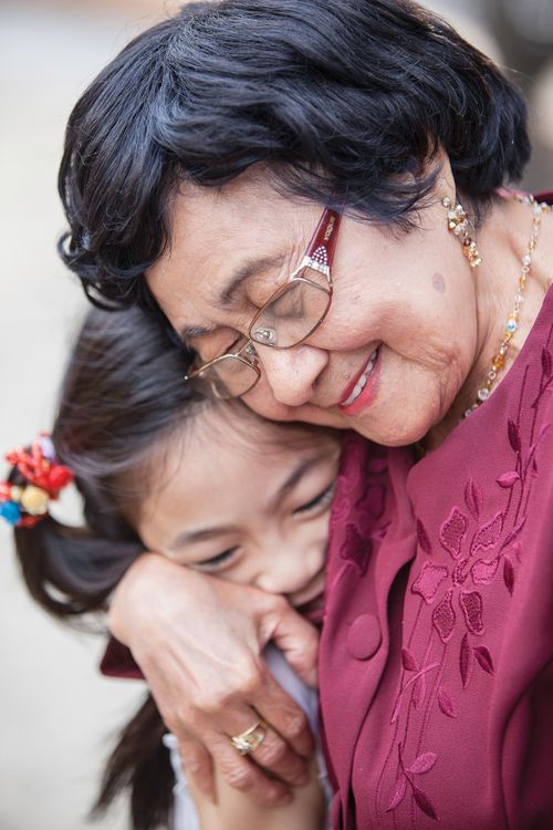 A portrait of an elderly woman hugging her young granddaughter.