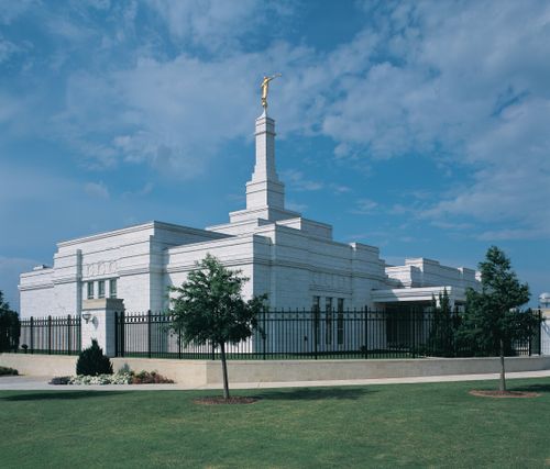 The Oklahoma City Oklahoma Temple on a sunny day, with a black fence around the perimeter of the grounds.