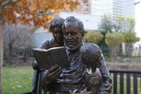 A statue of Brigham Young reading a book to his children. The statue resides at the Brigham Young gravesite.