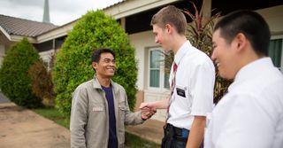des missionnaires serrent la main d’un homme