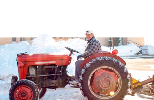 Ein Mann räumt mit dem Traktor Schnee