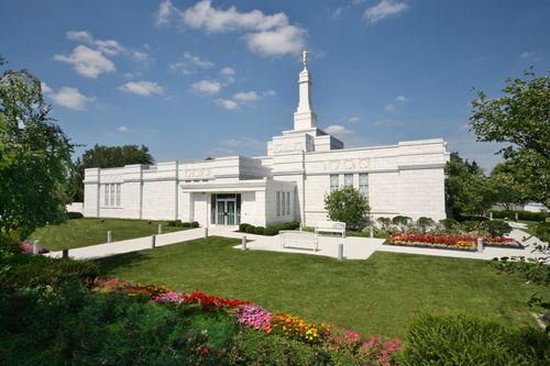 A green lawn, colorful flowers, and trees surround the Columbus Ohio Temple during the daytime.