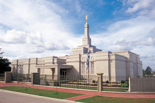 The sun lights up the flag, fences, and exterior walls of the Montevideo Uruguay Temple.