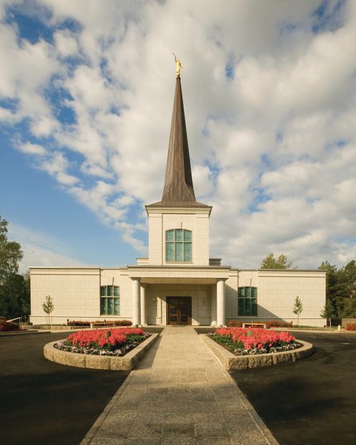 The path leading to the front entrance of the Helsinki Finland Temple, with flower beds in half circles on either side.