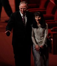Elder Neil L. Andersen waves to members in the audience as he and his wife walk together after a session of conference.