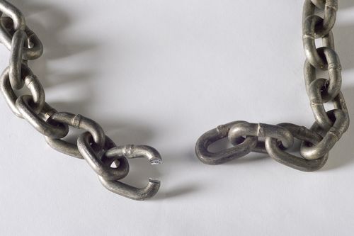 A heavy metal chain against a white background, shown with one link broken, which has separated the entire chain.