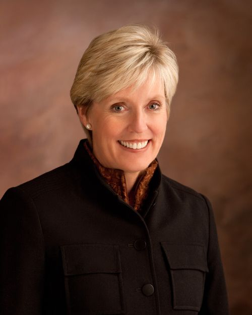 A photograph of Rosemary M. Wixom against a brown background, wearing a black blazer.