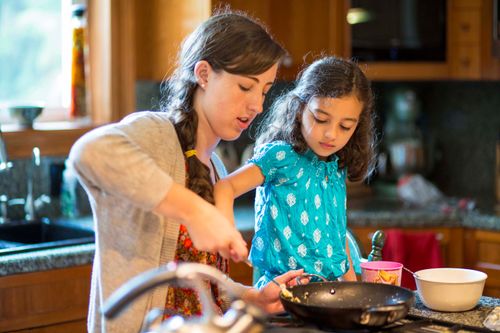young woman helping child cook