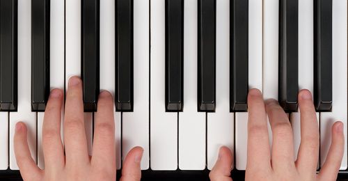 The keys of a piano being played by a young woman.