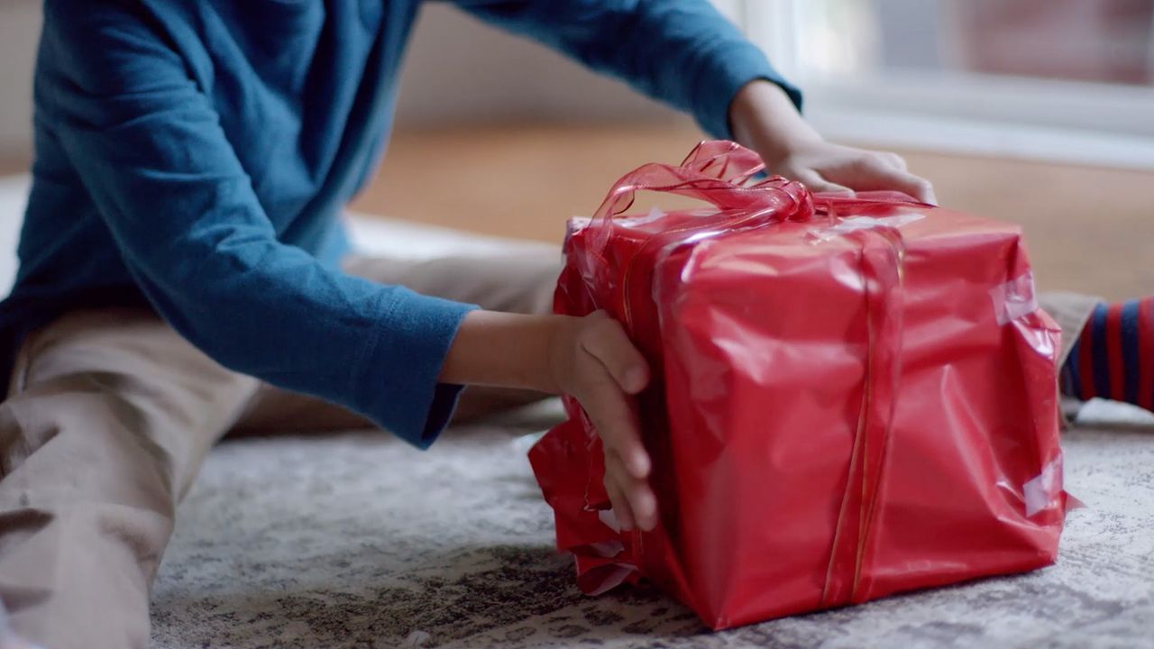 A young boy wraps a Christmas gift