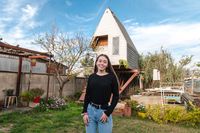 Natalie Bernales stands outside in her yard. Behind her is a home. This is in Chile.&nbsp;