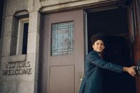 Um homem segura a porta aberta para uma família entrar em um edifício da Igreja