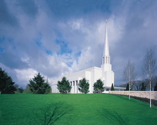 A view of the Preston England Temple from across its large green lawn on a partly cloudy day.
