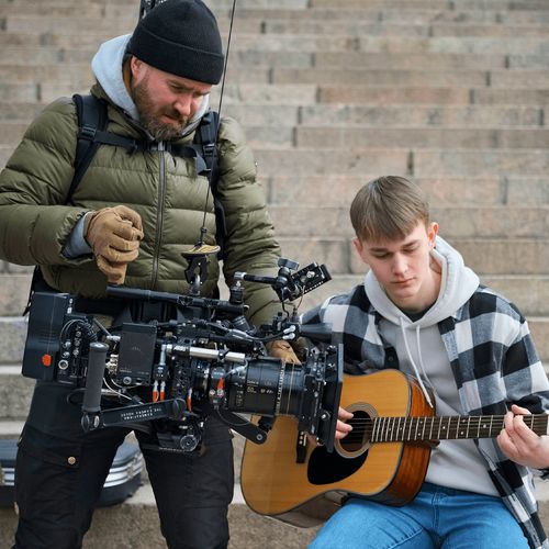 homem a filmar um rapaz a tocar guitarra